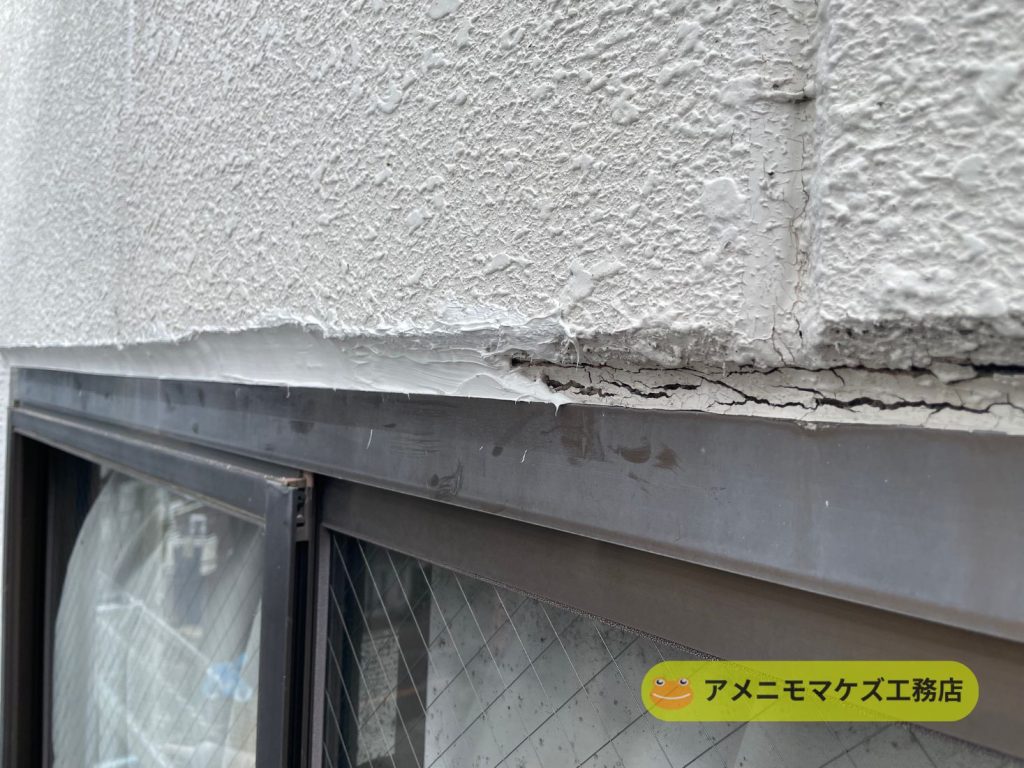窓上の外壁とサッシ取り合い部分でコーキングがひび割れている様子
